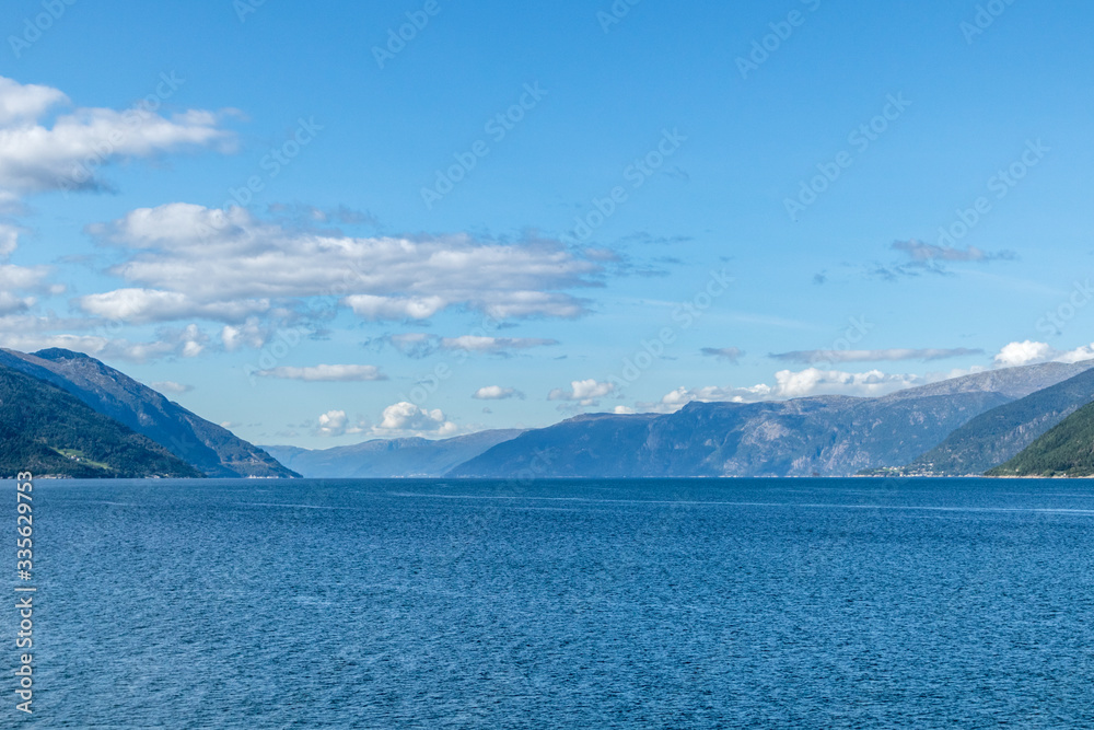 Bright blue vivid cold northern Norway fjord sea landscape. Clear sunny bluish nature view, faraway mountains 