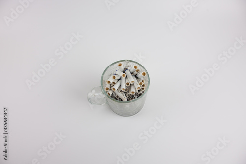 Cigarette butts in a mug on a white background