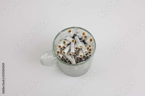 Cigarette butts in a mug on a white background