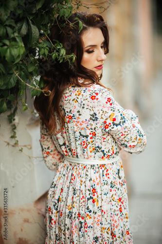Beautiful brunette sexy tourist girl walking on busy city street with long hair flying in the wind.