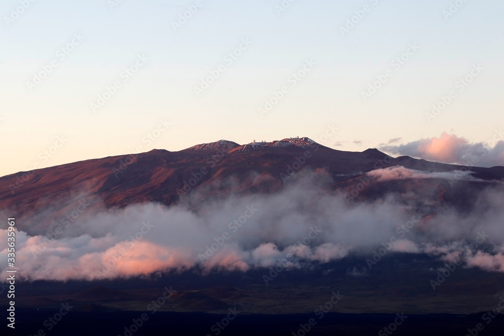 Hawaii Big Island nature background. Scenic landscape with Mauna Kea peak with observatories above the clouds. Amazing view from Mauna Loa during sunset.