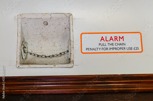 Passenger alarm chain inside an old fashioned railway carriage, and sign warning about improper use