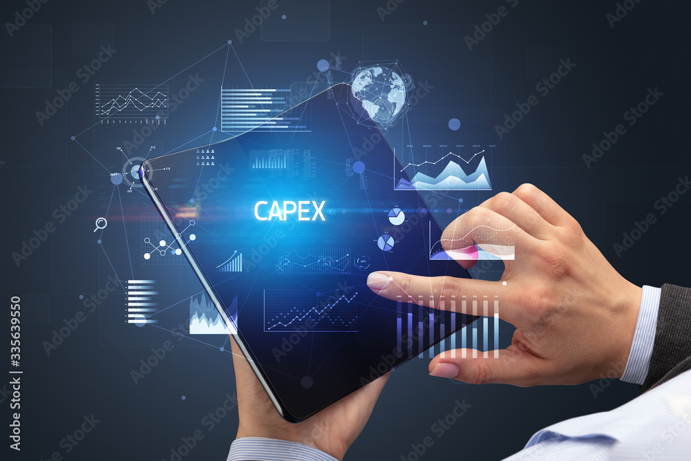 Businessman holding a foldable smartphone with CAPEX inscription, successful business concept Businessman holding a foldable smartphone with CAPEX inscription, successful business concept