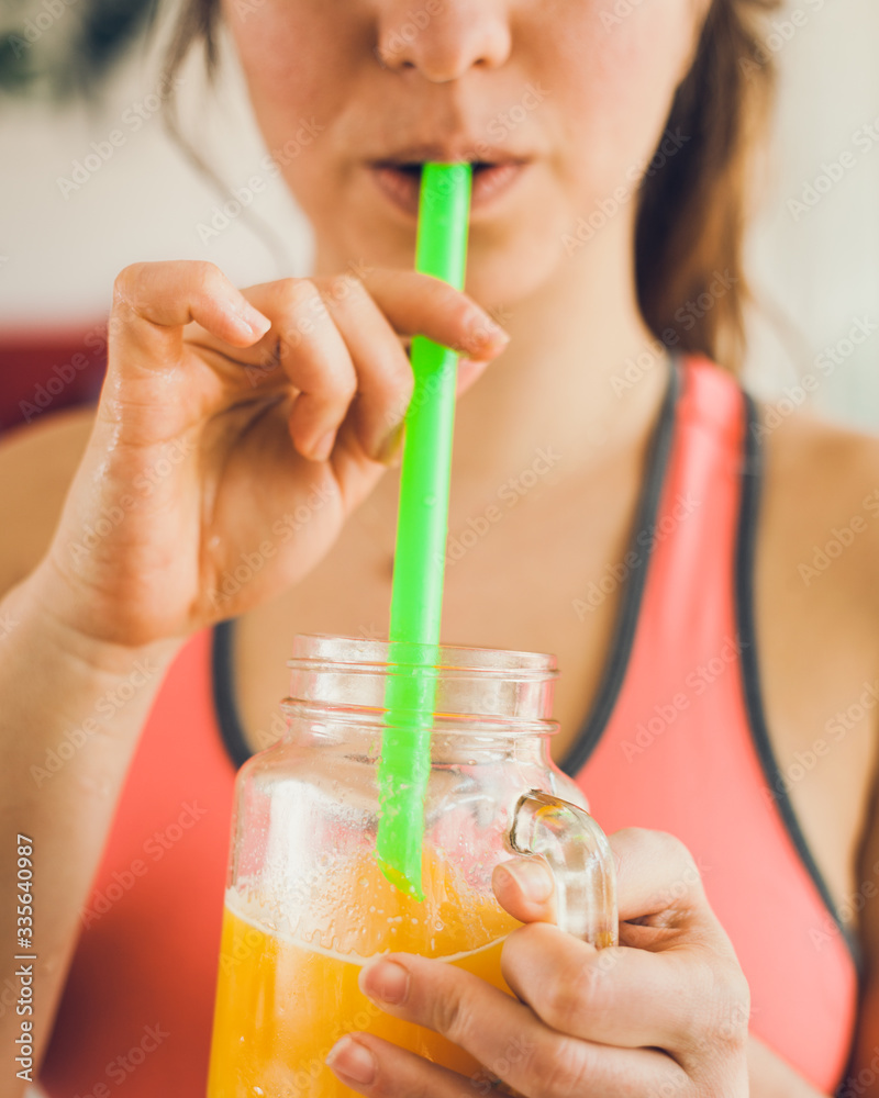 Young woman in sportswear drinking freshly squeezed orange juice. 
