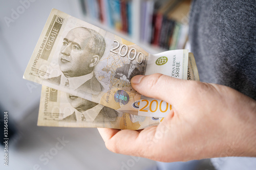 High angle close up view of unknown caucasian man midsection holding 2000 Serbian Dinar RSD banknotes money savings in hand in day