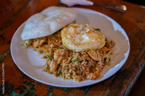 Balinese dinner served in a white plate with mixed seafood friedrice and egg