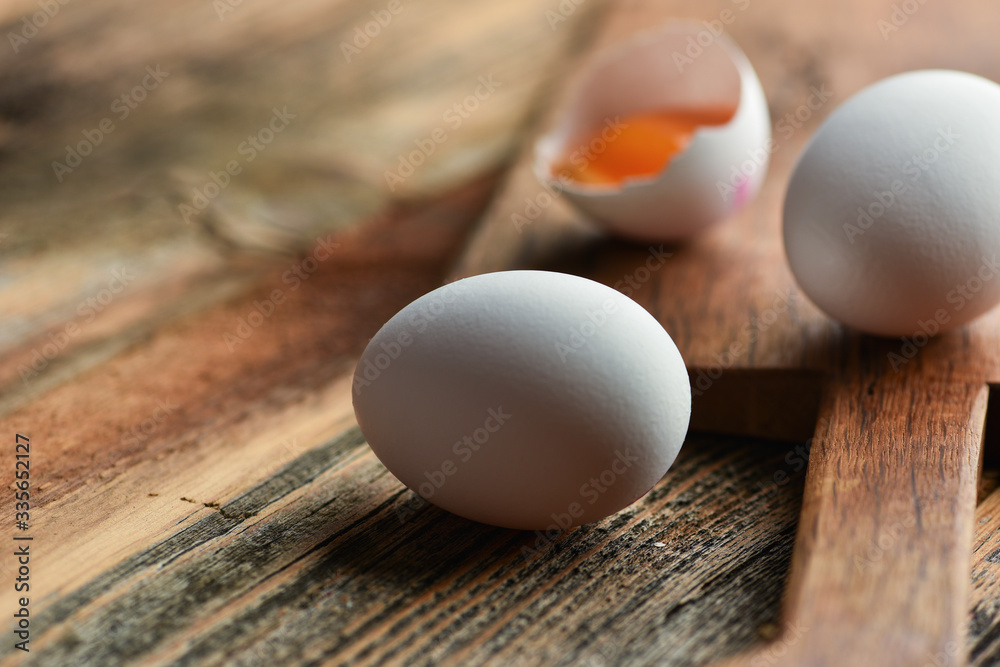 Chicken eggs and half broken egg with yolk on wooden background. Chicken eggs and half broken egg with yolk on wooden background.