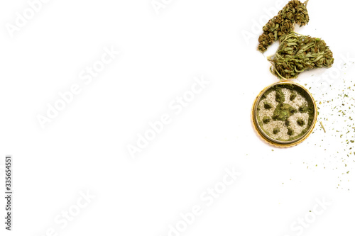 Several perfectly died green cannabis buds and metal grinder isolated on white background. 