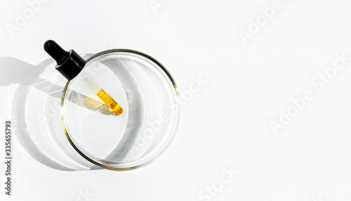 A liquid yellow serum or oil in a dropper on white background with copy space. Natural cosmetic. Face, skin care. Health and beauty, anti-age, aging concept. Close-up. Minimalism flat lay. photo