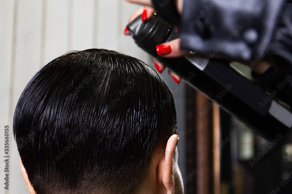 Fototapeta premium Makeup artist does hairstyle to a girl with beautiful black short hair. Beauty and fashion industry. Gel polish for hair. Shine and glow