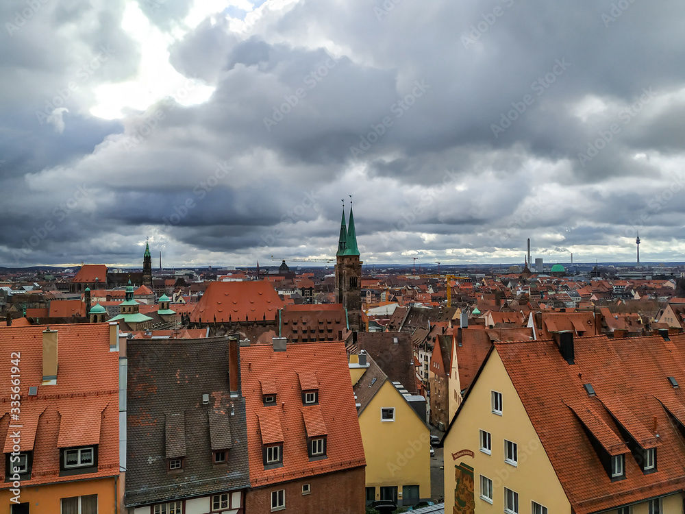 Fototapeta premium View from the high tower of the old part of the modern city, the beautiful roofs of brick shades and the sky before a thunderstorm.