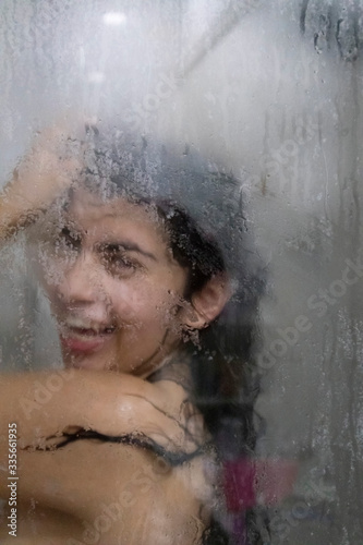 Artistic photo of a beautiful latin woman taking a shower with a big smile