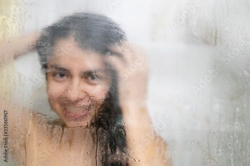 Artistic photo of a beautiful latina woman taking a shower with a big smile