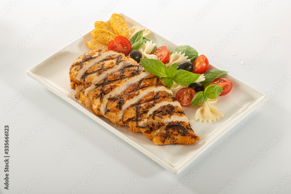 Italian style marinated chicken breast with fresh salads and tomato catchup on a white rectangle plate