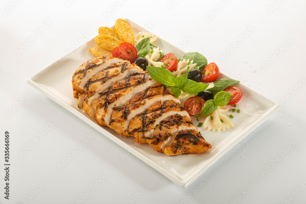 Italian style marinated chicken breast with fresh salads and tomato catchup on a white rectangle plate