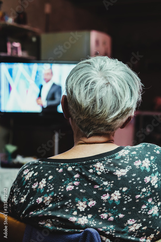 senior woman from back watching television at home