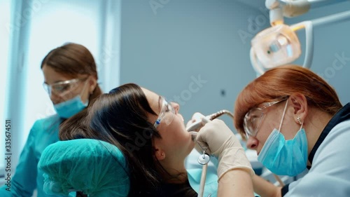Wallpaper Mural Dental oral procedure in dentistry. Female stomatologist and a nurse in masks treating patient's tooth in modern clinic. Torontodigital.ca