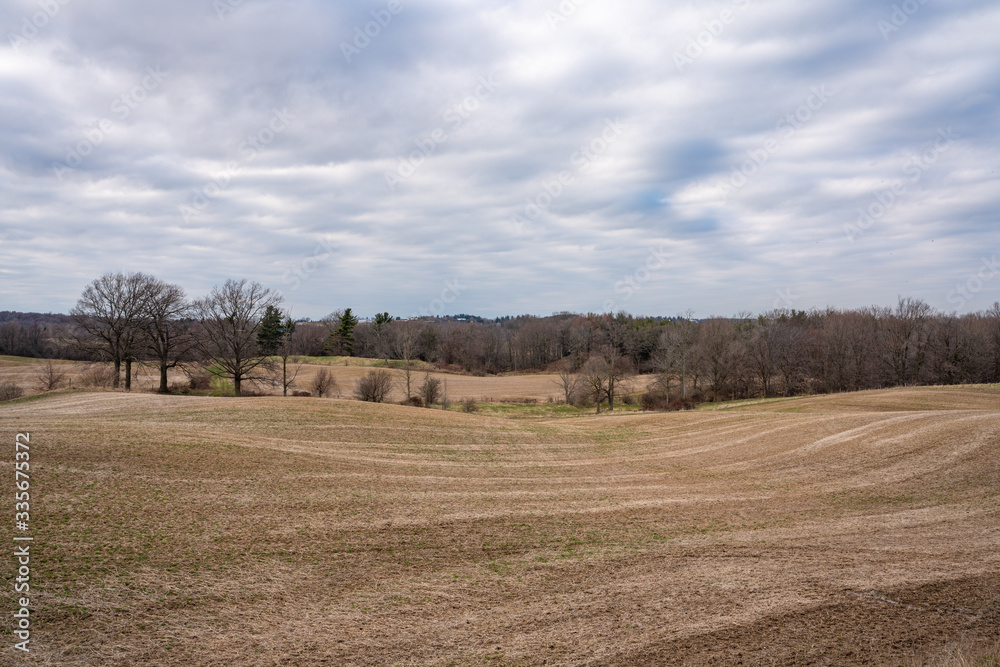 Rolling hills landscape with farmland, trees and blue sky taken during cloudy weather in spring Rolling hills landscape with farmland, trees and blue sky taken during cloudy weather in spring