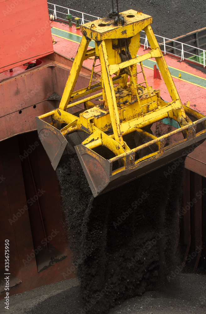 Loading coal from cargo barges onto a bulk vessel using ship cranes in offshore coal cargo terminal.
Loading coal from cargo barges onto a bulk vessel using ship cranes in offshore coal cargo terminal.