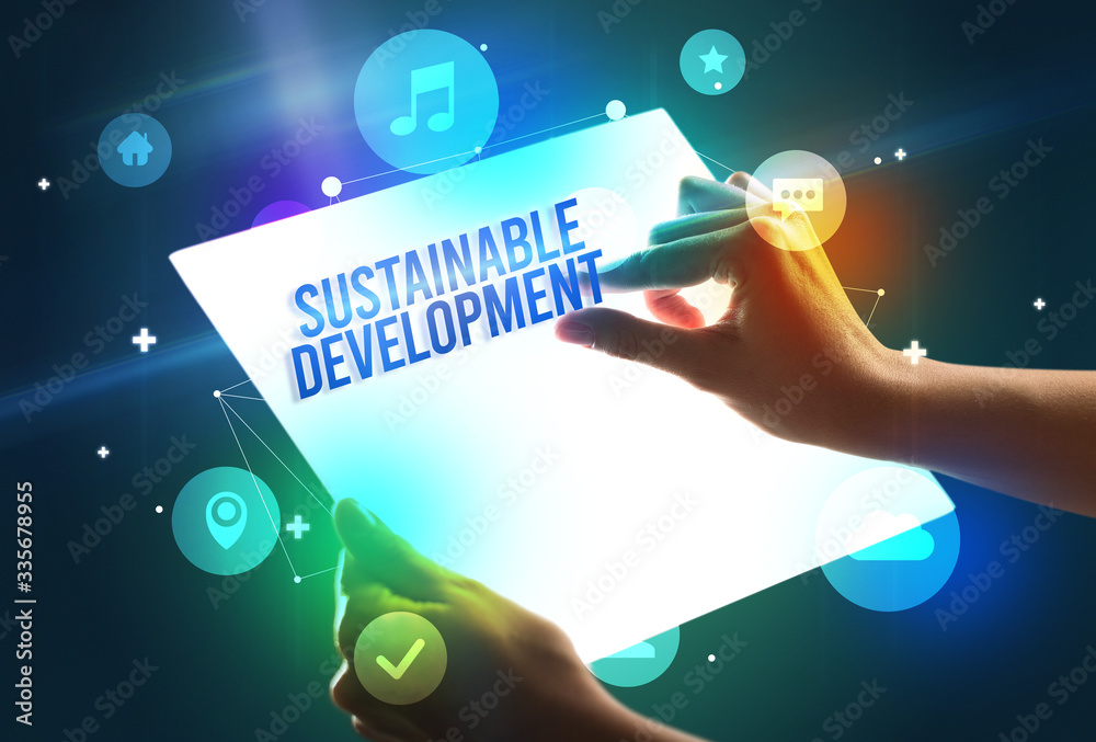 Holding futuristic tablet with SUSTAINABLE DEVELOPMENT inscription, new technology concept Holding futuristic tablet with SUSTAINABLE DEVELOPMENT inscription, new technology concept