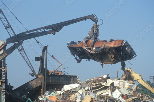 A wrecking crane lowering a demolished automobile onto a pile of junk, Atlanta, Georgia