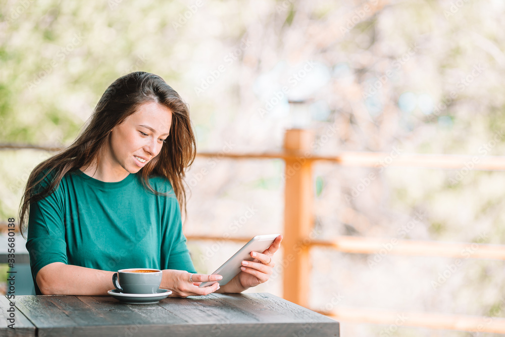 Beautiful woman having breakfast at outdoor cafe. Happy young urban woman drinking coffee Beautiful woman having breakfast at outdoor cafe. Happy young urban woman drinking coffee