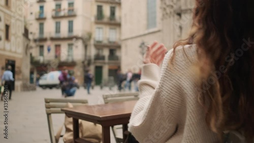 Conceptual tracking around shot of beautiful girl resting with glass of red wine in cozy cafe on city square