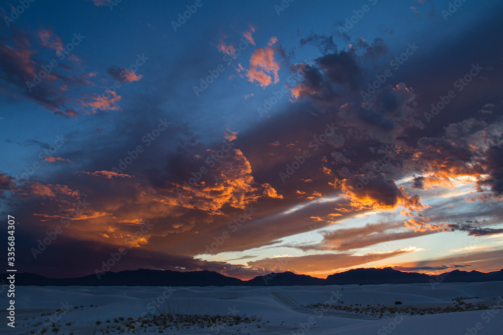 Bright clouds at sunset over the dunes of white sands