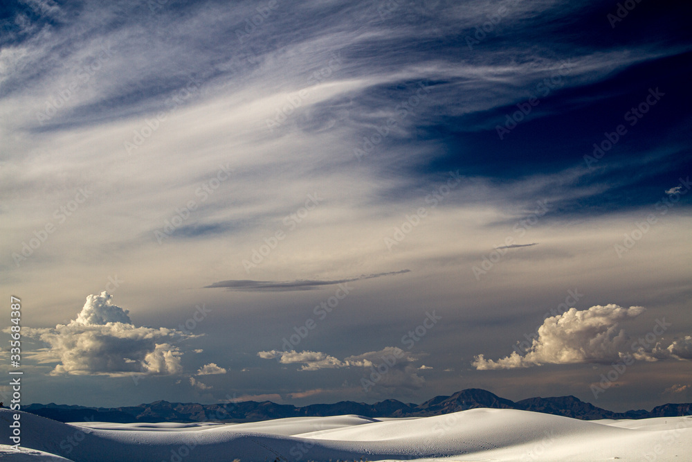 wispy and storm clouds rise high above the sand dunes wispy and storm clouds rise high above the sand dunes