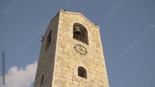A bell tower in a stabilized zoom shot that revolves around the building, in the background the cloudy blue sky, medium shot, Full HD slow motion video