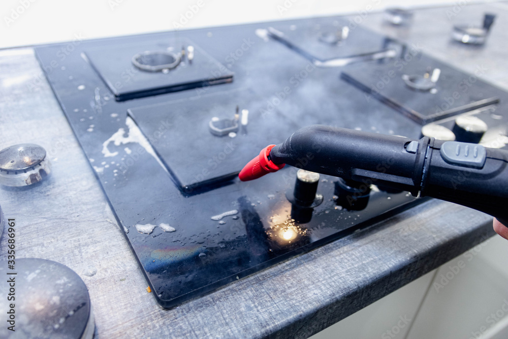 steam cleaner cleans the stove in the kitchen and disinfects the surface.