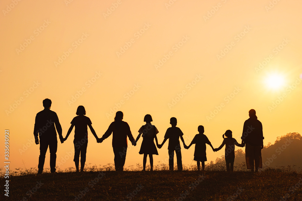 Fototapeta premium Silhouette of happy family standing on the mountain at the sunset time.