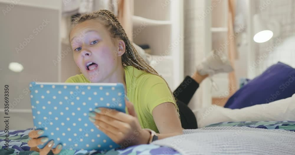 Young teenage blonde girl with dreadlocks makes video conference call using tablet PC with boyfriend or parents. Self-isolation during coronavirus epidemic. Stay home, chatting online. Remote services Young teenage blonde girl with dreadlocks makes video conference call using tablet PC with boyfriend or parents. Self-isolation during coronavirus epidemic. Stay home, chatting online. Remote services