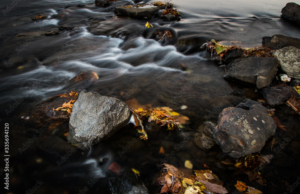 Tightly framed image of stones, autumn leaves and flowing water in the Schuylkill River