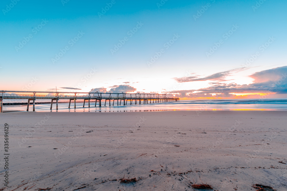 Fototapeta premium Sunrise over bridge with waves crashing take at Gold Coast Australia