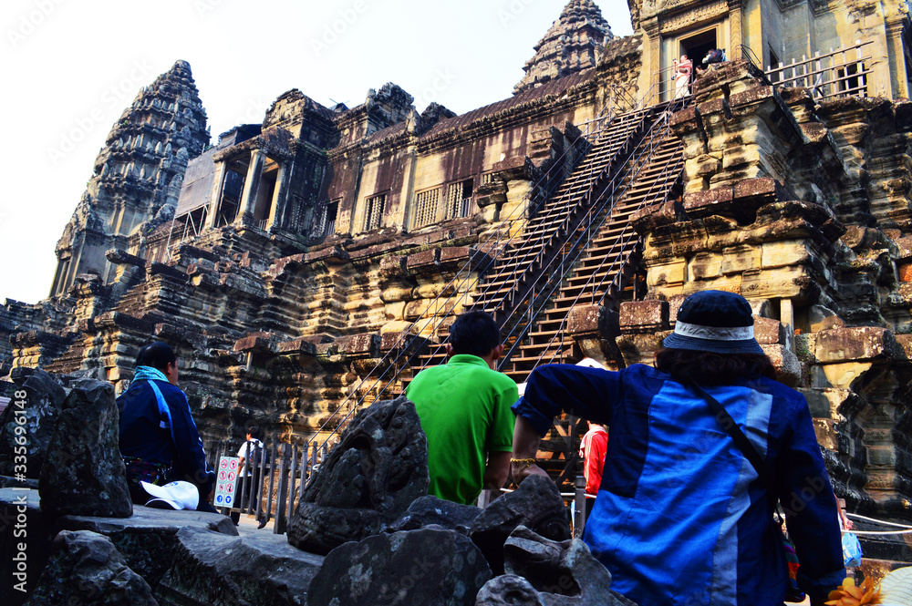 Obraz premium Travelers rest on ground seeing high wall of a temple