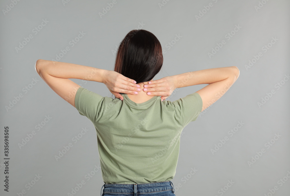 Woman suffering from pain in neck on light grey background. Visiting orthopedist Woman suffering from pain in neck on light grey background. Visiting orthopedist