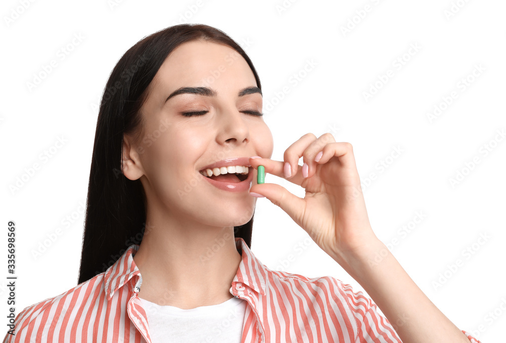 Young woman taking vitamin capsule on white background Young woman taking vitamin capsule on white background