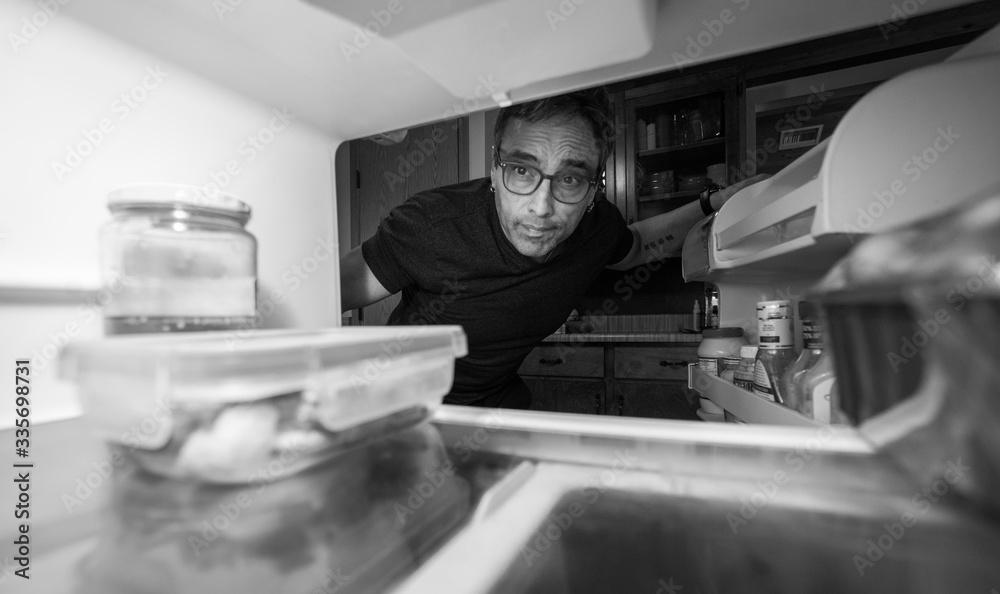 Man staying at home looking in an empty fridge for something to eat while in quarantine self isolation Man staying at home looking in an empty fridge for something to eat while in quarantine self isolation