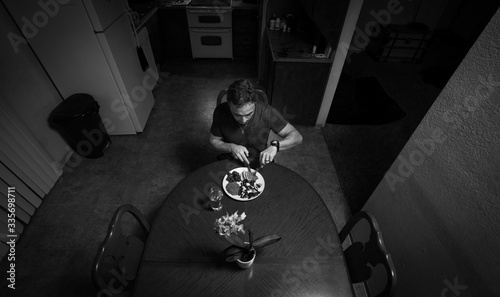 Man staying at home eating dinner alone while in quarantine during self isolation