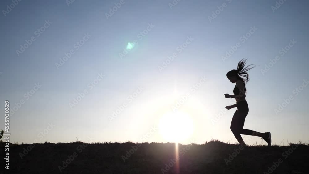 The silhouette of a woman in black clothes running and then stopped to catch the knee with pain and keep running The silhouette of a woman in black clothes running and then stopped to catch the knee with pain and keep running