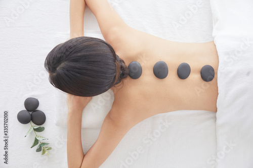 SPA relaxation. Top view of women relaxing at SPA, receives a spa massage with black hot stones placed on her back.
