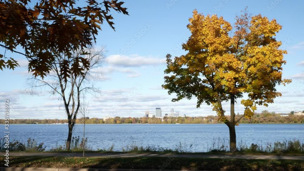 The Minneapolis, Minnesota skyline and beautiful autumn foliage and foot and car traffic on the parkway of Lake Calhoun or Lake Bde Maka Ska. The Minneapolis, Minnesota skyline and beautiful autumn foliage and foot and car traffic on the parkway of Lake Calhoun or Lake Bde Maka Ska.
