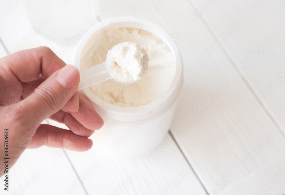 hand holding scoop of fish collagen. collagen peptides in container or jar. Copy space for text. Healthcare supplement concept. close up view on wooden background. hand holding scoop of fish collagen. collagen peptides in container or jar. Copy space for text. Healthcare supplement concept. close up view on wooden background.
