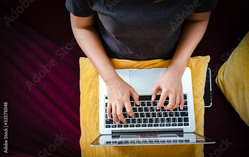 Young woman working on laptop computer while sitting on the red sofa in living room at home, working from home concept.business concept background.