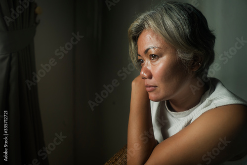sad and worried mature woman on living room couch feeling depressed and scared suffering middle age crisis and fear going through covid-19 home lockdown alone