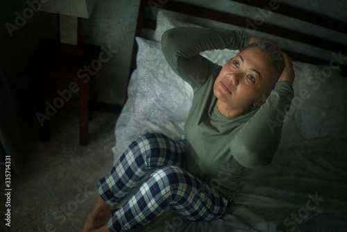 attractive middle aged woman with grey hair sad and depressed in bed feeling scared and lonely thinking worried about covid-19 virus pandemic during home lockdown