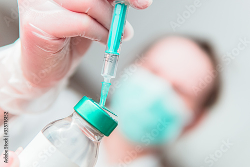 Immunization. Doctor with medical mask prepares vaccine against coronavirus covid-19 photo