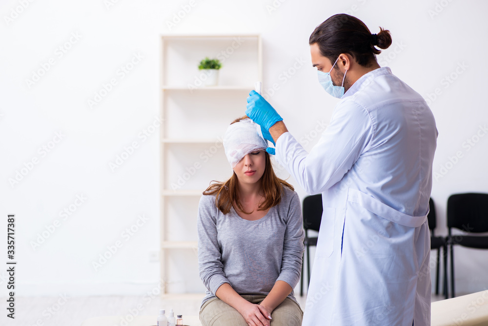 Young head injured woman visiting young male doctor Young head injured woman visiting young male doctor