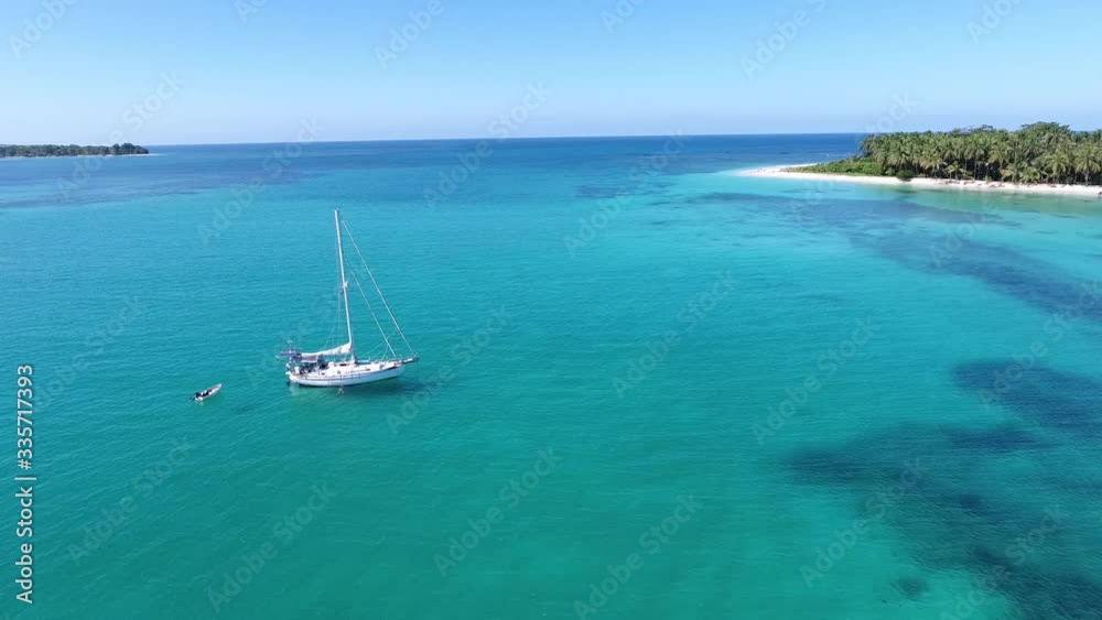 Sailboat in Aqua Colored Water Near Island Beach Shoreline Sailboat in Aqua Colored Water Near Island Beach Shoreline